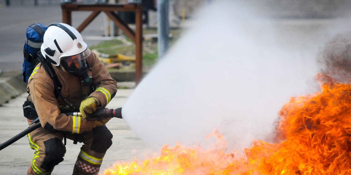 Firefighter tackling flames with hose