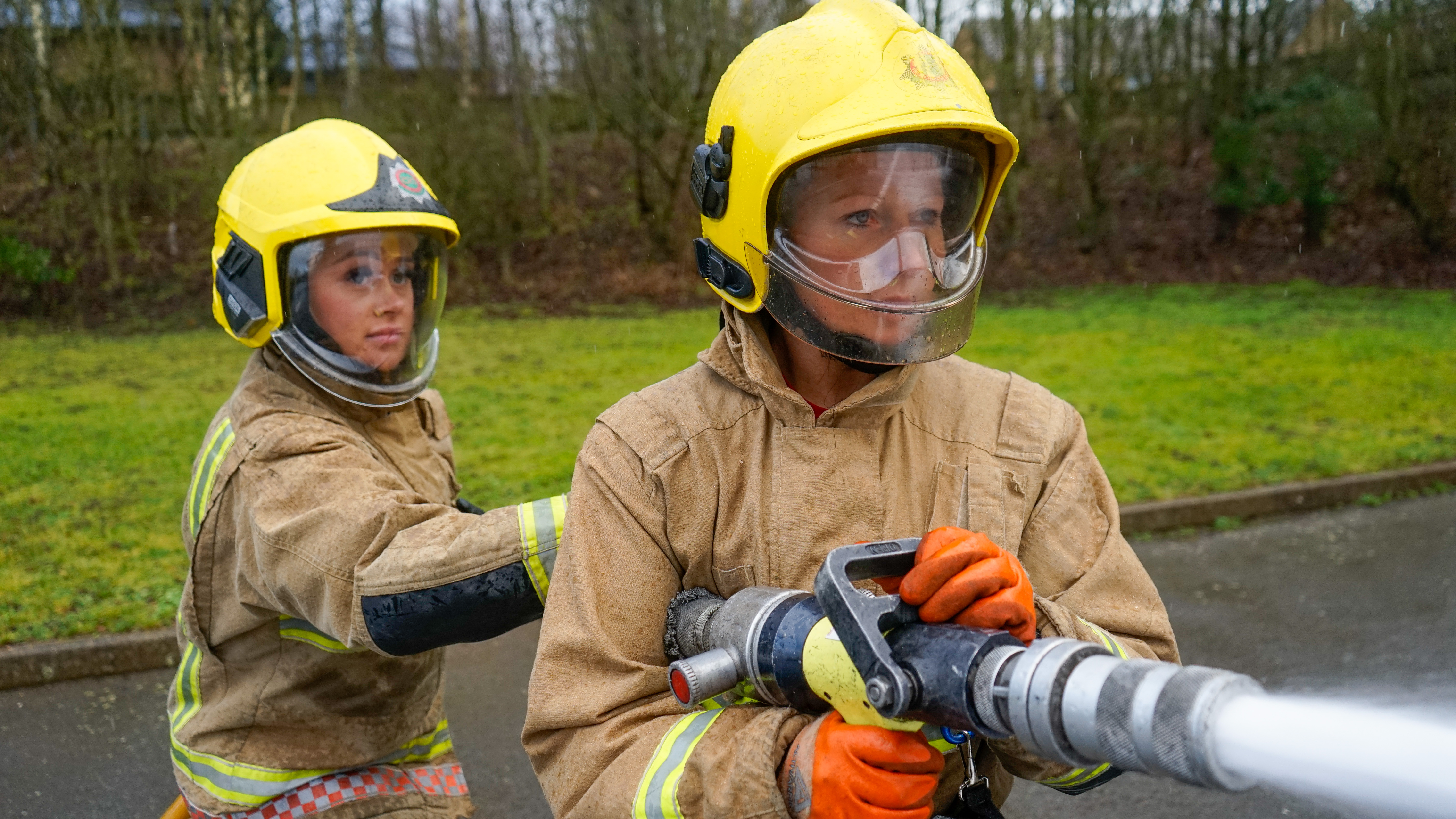Two female firefighters using hose